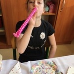 Uczennica dmucha w papierową trąbkę.