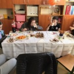 Uczennice siedzą wokół stołu i jedzą tort.