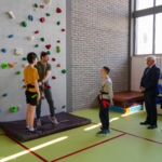 Pan prezydent Białegostoku Tadeusz Truskolaski i pani  dyrektor Jolanta Woińska  obserwują nauczyciela i uczniów przygotowujących się do wejścia na ściankę.