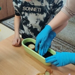 Uczeń sadzi cebulę w ziemi wsypanej do doniczki.