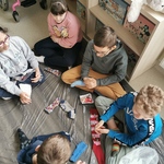 Uczniowie siedzą na dywanie. przed nimi leżą kolorowe skarpety.
