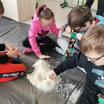 Uczniowie siedzą na dywanie. przed nimi górka z ryżu.