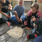 Uczniowie siedzą na dywanie. i wsypują ryż do skarpet.
