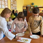 Uczniowie pomagają nauczycielce układać kolorowe cukierki na talerzu w celu przeprowadzenia eksperymentu.
