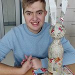 Uczeń siedzi przy stole. Przed nim stoi butelkowy zając oklejony kawałkami gazety.