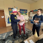 Nauczycielka wręcza prezent jubilatowi. Obok stoi kolega z klasy.