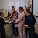 Grupa dzieci i nauczycielka składają życzenia chłopcu.