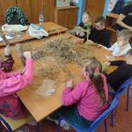 Uczniowie siedzą wokół stołu na którym leży słiano.