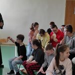 Ksiądz częstuje uczniów chlebem.