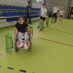 Uczniowie ćwiczą na sali gimnastycznej - wykonują slalom.