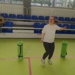 Uczennica tańczy na sali gimnastycznej. Obok stoją dwie karimaty.