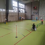 Uczniowie ćwiczą na różnych stanowiskach na sali gimnastycznej.