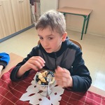 Uczeń siedzi za stołem. Przed nim stoi pucharek z płatkami i owocowymi dodatkami.