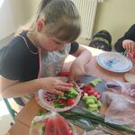 Uczennica kladzie na kanapkę.pokrojone nowalijki leżące obok.