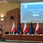 Sala konferencyjna Podlaskiego Urzędu Wojewódzkiego. Slajd wyświetlony na ekranie. Przy mównicy stoi kobieta.