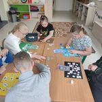 Uczniowie siedzą wokół stołu i uzupełniają tematyczne kart pracy.