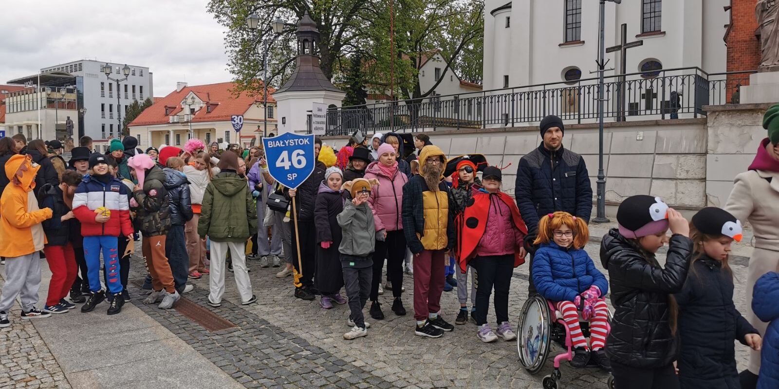 Grupa uczniów w przebraniach idzie w pochodzie.