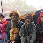 Uczniowie w przebraniach siedzą na tylnym siedzeniu w autobusie.