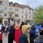 Grupa uczniów w przebraniach stoi na placu przed ratuszem.