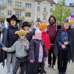 Grupa uczniów w przebraniach stoi przed ratuszem.