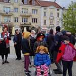 Grupa uczniów w przebraniach stoi na placu  przed ratuszem.