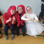 Dwoje uczniów w przebraniu krasnoludków siedzi obok koleżanki w stroju królewny