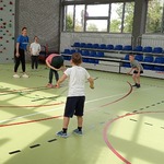 Grupa uczniów i nauczycielki grają na sali gimnastycznej w skakańca.