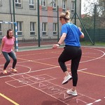 Grupa uczniów i nauczycielki grają w pana na boisku szkolnym.