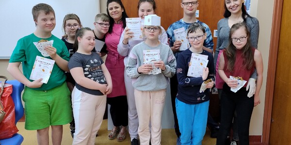 Uczniowie stoją w grupie i prezentują dyplomy z warsztatów.