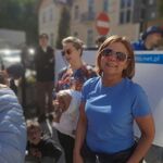 Kobieta w niebieskiej bluzce i okularach  uczestnicząca w marszu.