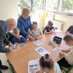 Uczniowie z pomocą babci Marysi i dziadka Bartka wykonują pracę plastyczną.