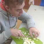 Uczeń kroi nożem jabłko na kawałki.