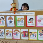 Pani pedagog rozmawia z pacynką z za tablicy z kolorowymi obrazkami.
