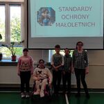 Grupa uczniów na tle wyświetlanego slajdu z napisem - Standardy ochrony nieletnich.