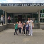 Grupa uczniów i nauczycielka stoją przed wejściem do Teatru Lalek