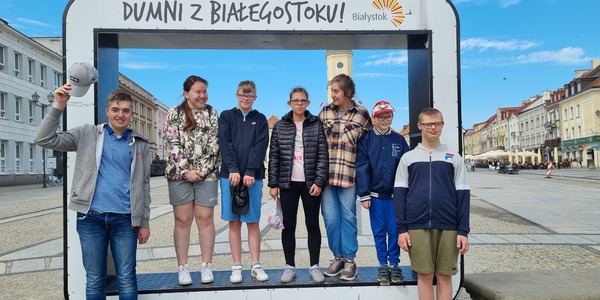 Grupa uczniów stoi w okienku z napisem "Dumni z Białegostoku ".
