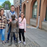 Troje uczniów stoi przy figurce esperanto.