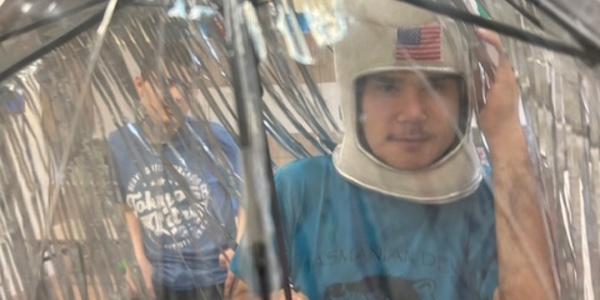 Uczeń w czapce astronauty stoi pod parasolem.