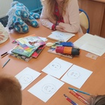 Autorka siedzi przy stole, przed nią leżą obrazki z narysowanymi emocjami.