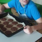 Uczeń siedzi przy stoliku, przed nim leży blacha z ciastkami.