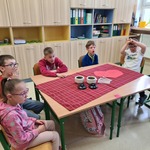 Uczniowie siedzą przy stoliku, na stole leżą pojemniki z herbatą.