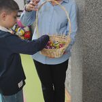 Pani Dyrektor częstuje ucznia cukierkami z koszyczka.