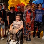 Grupa uczniów na tle kolorowych balonów.