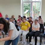 Uczennica w trakcie wykonywania zadania konkursowego. Z tyłu na krzesłach siedzą uczestnicy konkursu.