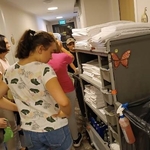 Grupa uczniów ogląda wózek hotelowy z bielizna pościelową.
