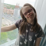 Uczennica stoi przy oknie z którego widać panoramę miasta.