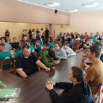 Uczestnicy turnieju siedzą wokół stołów.