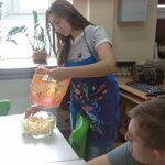 Uczennica wsypuje chrupki do miski.