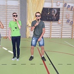 trójka uczniów w słonecznych okularach śpiewa do mikrofonów.