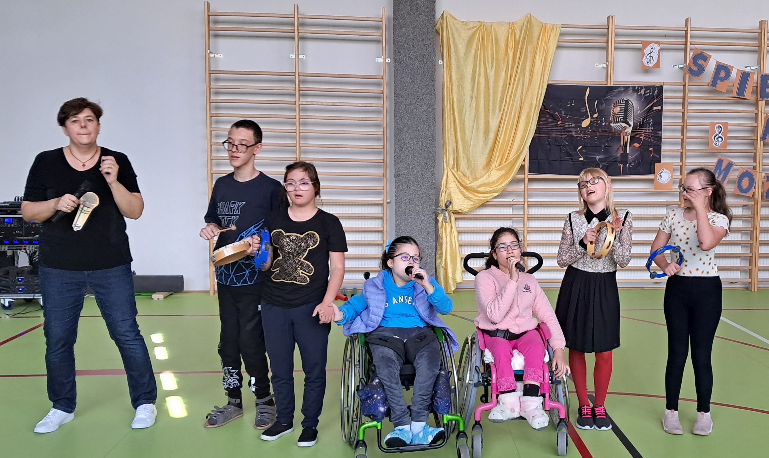Nauczycielka i grupa uczniów w trakcie występu.